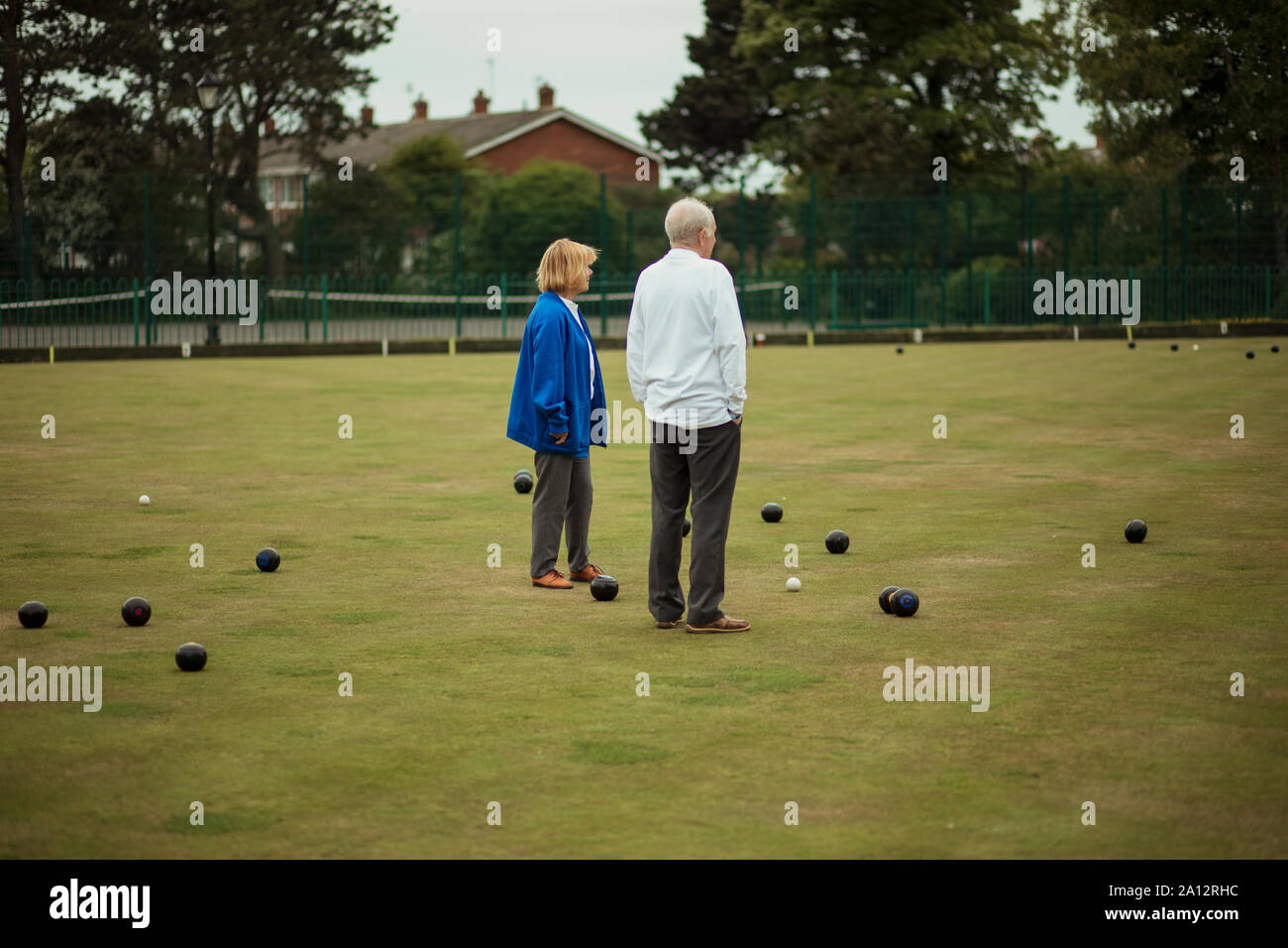 Zwei ältere Erwachsene gemeinsam in der Mitte eines Bowling Green, von Boccia Kugeln umgeben. Stockfoto