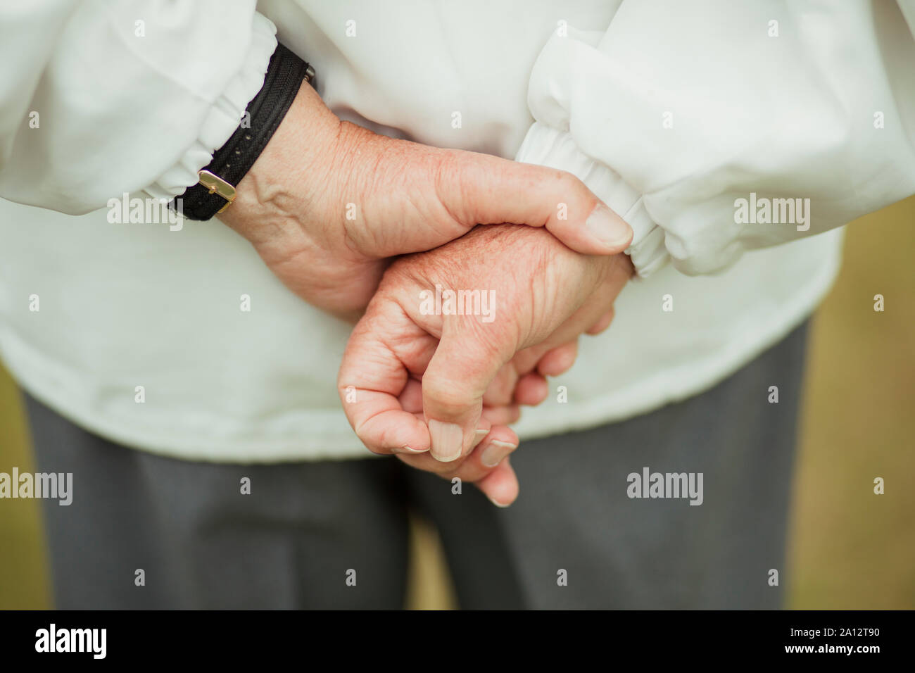 Eine Nahaufnahme von den Händen ein älterer Mann, der hinter seinem Rücken, sie zusammenzuhalten. Stockfoto
