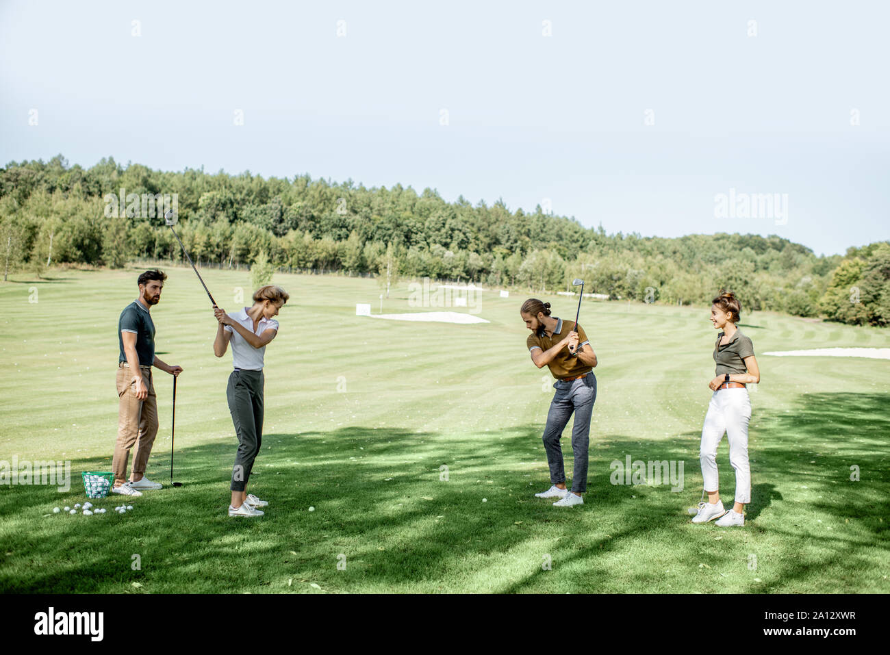 Gruppe von einem jungen Menschen lässig gekleidet, Golf spielen auf dem Golfplatz an einem sonnigen Tag, Mann und Frau, das Schwingen einer Putter Stockfoto