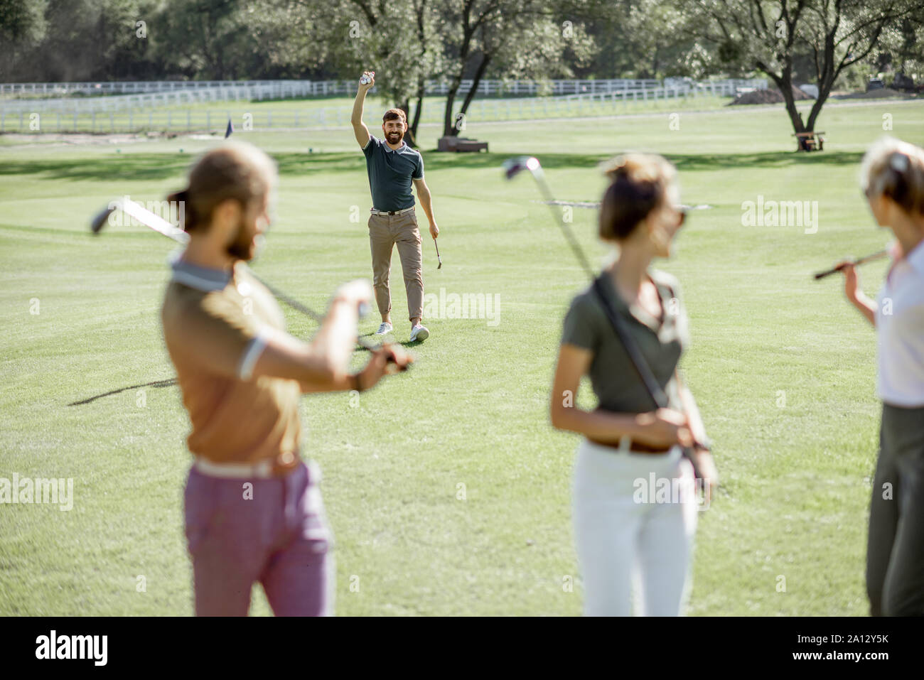 Junge Freunde lässig gekleidet gehen mit Putter auf dem Golfkurs während eines Spiels an einem sonnigen Tag Stockfoto