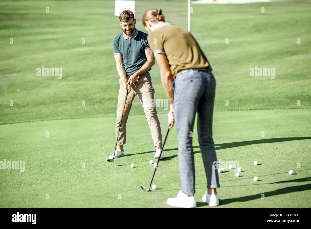Zwei Männer spielen Golf, schoss den Ball mit dem Putter in die Bohrung auf dem Kurs, der an einem sonnigen Tag Stockfoto