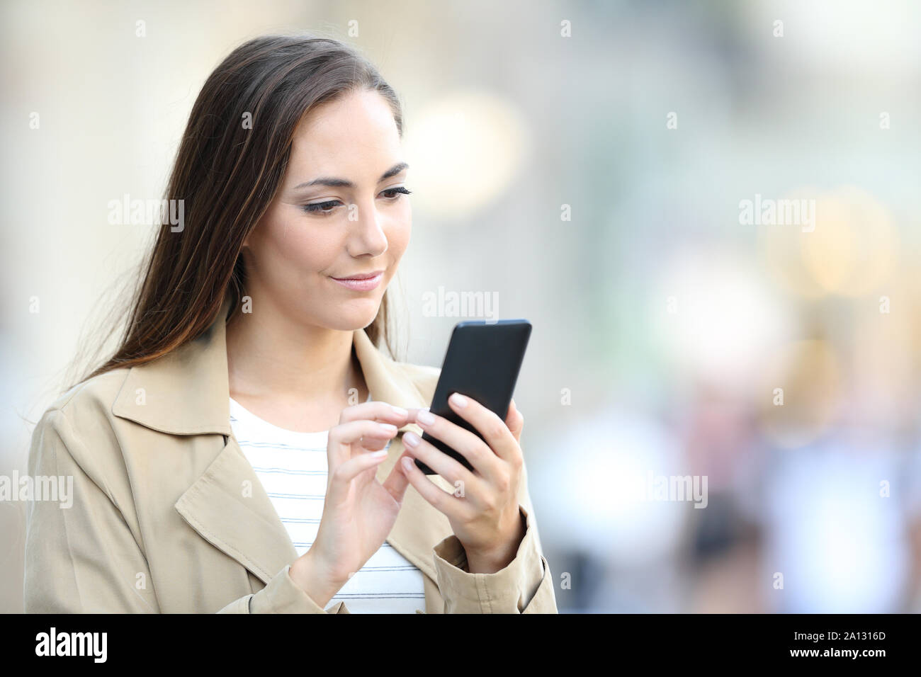 Ernsthafte lady Surfen smart phone Online Content zu Fuß auf der Straße Stockfoto