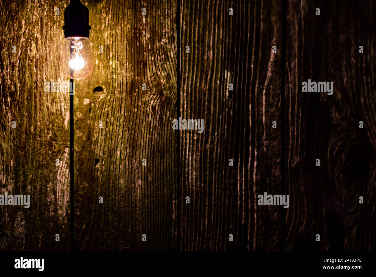 Glühbirne gegen eine alte plank Zaun bei Nacht mit Zimmer auf der rechten Seite für Text Stockfoto