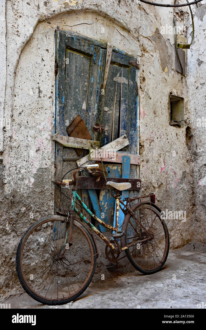 Altes, rostiges Fahrrad gegen einen verfallenen Marokkanischen Tür geparkt zu einem typischen Kalk getünchte Wand in die Quintessenz der Stadt Essaouira, Marokko, Afrika. Stockfoto