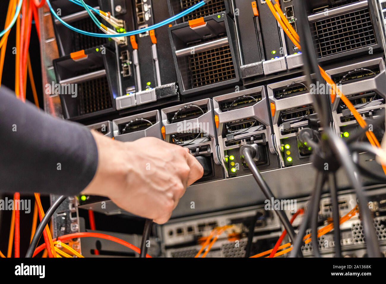 Techniker, der das Netzkabel an den Blade-Server-Cluster im Rechenzentrum anschließt Stockfoto