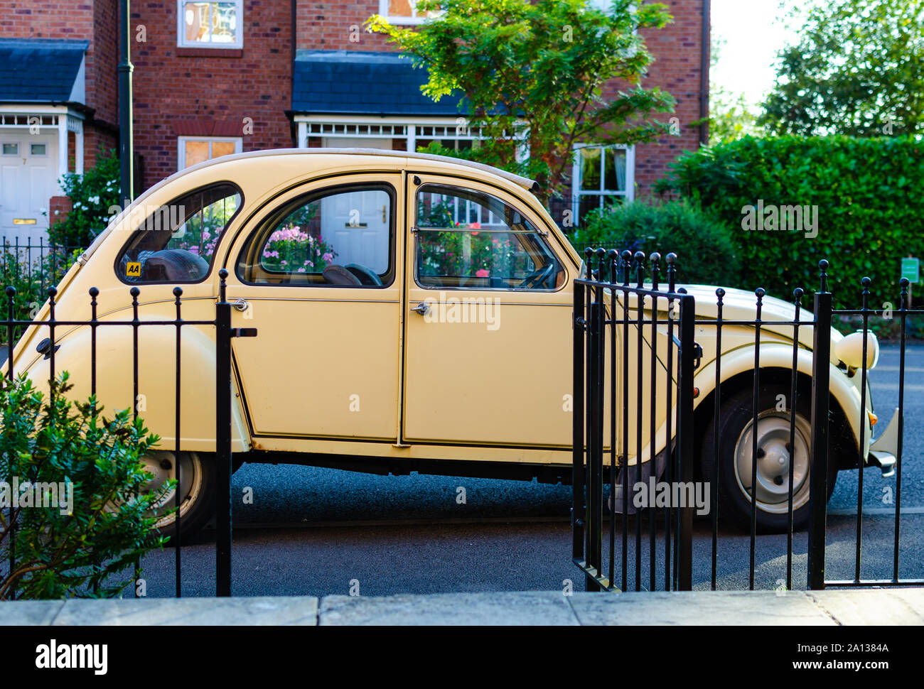 Die classic car Citroën 2CV neben einem malerischen Haus in England geparkt. Stockfoto