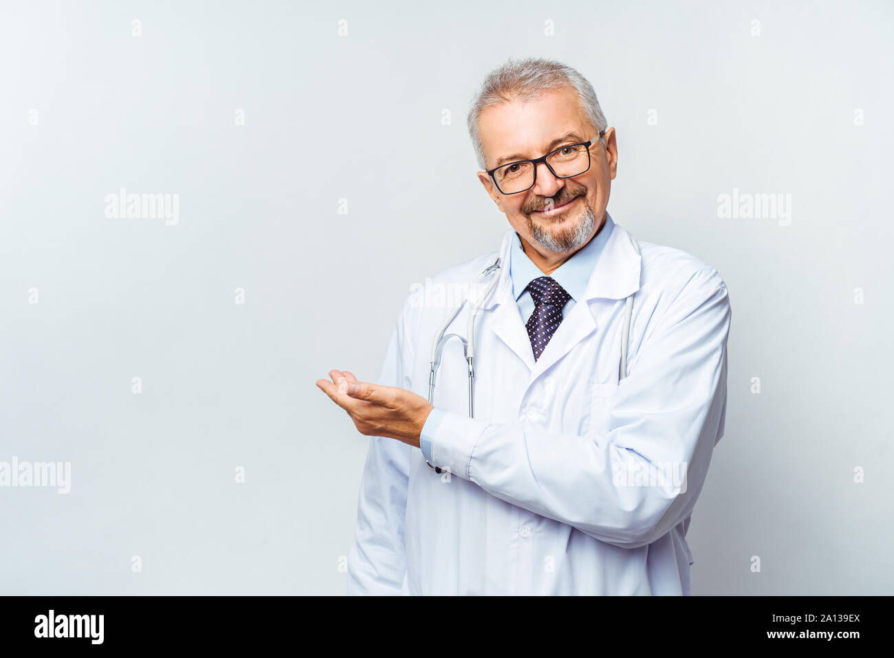 Fröhliche reife Arzt posing und lächelnd an Kamera, Gesundheitswesen und Medizin. Stockfoto