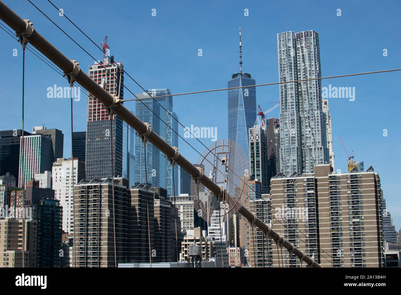 Blick auf die Skyline von Lower Manhattan mit der Stahlkonstruktion der Brooklyn Brücke im Vordergrund. Das One World Trade Center und Gehry Berndorf sieht Stockfoto