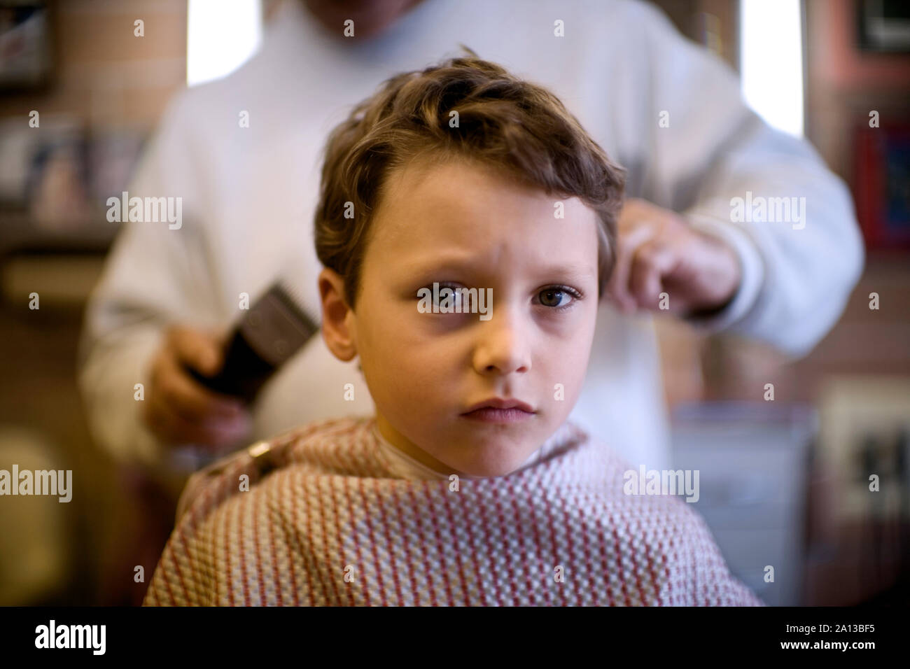 Blick auf einen kleinen Jungen in einen Haarschnitt von einem Friseur. Stockfoto