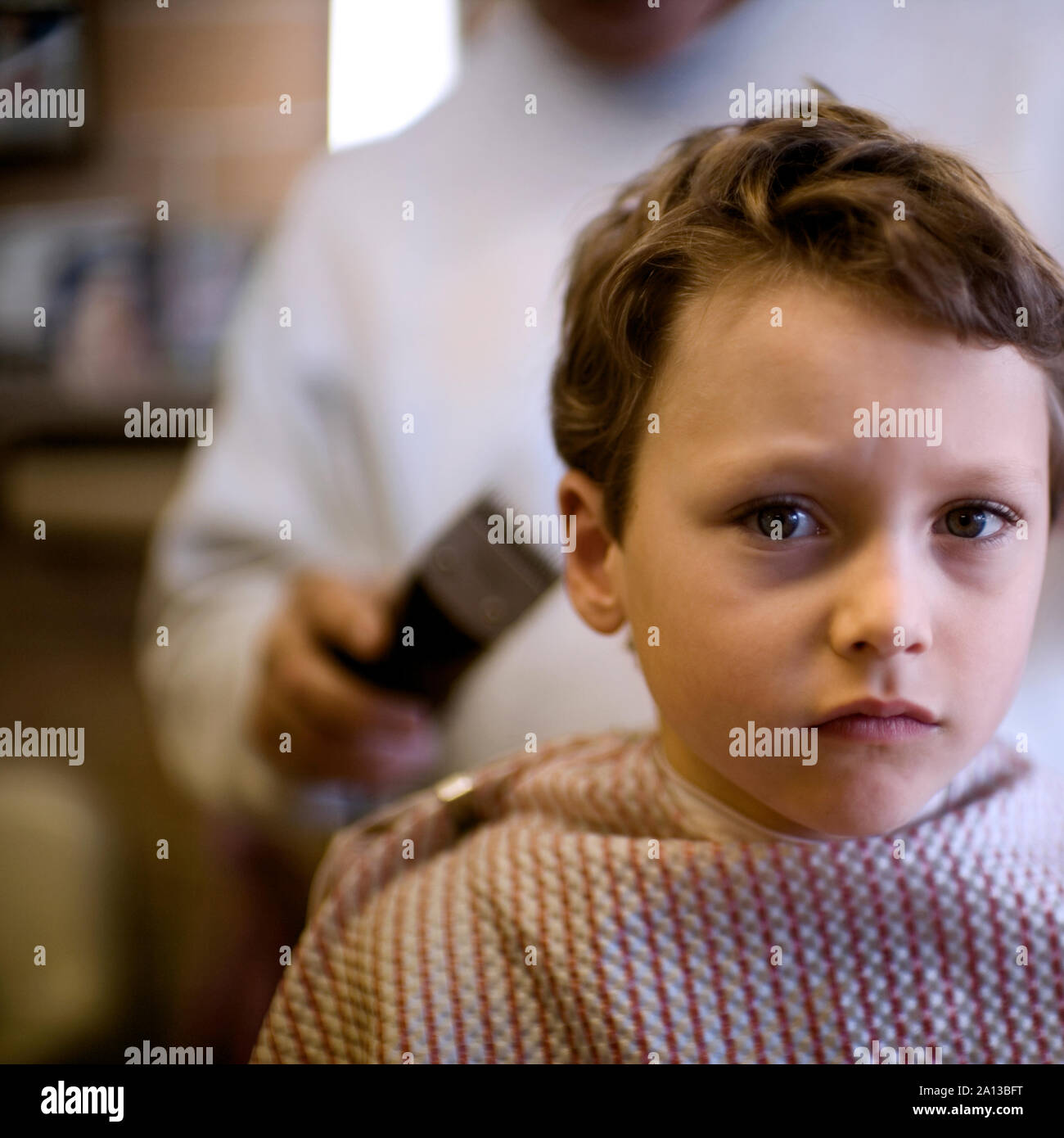 Blick auf einen kleinen Jungen in einen Haarschnitt von einem Friseur. Stockfoto