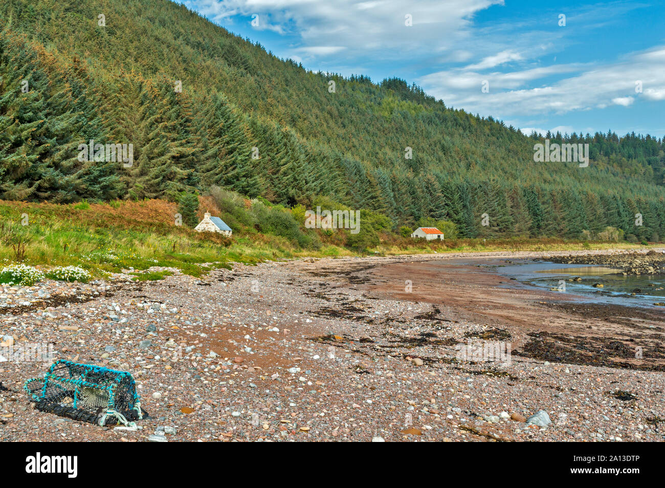 ROSEMARKIE zu CROMARTY SPAZIERGANG BLACK ISLE SCHOTTLAND BUCHT UND STRAND MIT ZWEI LACHS BOTHIES ODER GEBÄUDEN UND WALD VON TANNEN Stockfoto