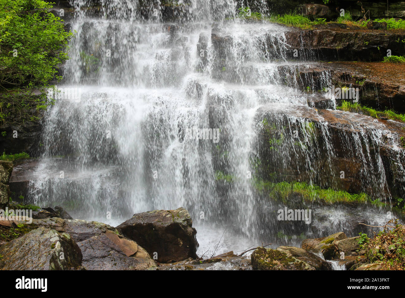 Schöne Nahaufnahme der beeindruckende Wasserfall Tupavica auf alten Berg, in der Nähe von Dojkinci, mit klaren grünen Moos, Spritzwasser und roten Felsen Stockfoto