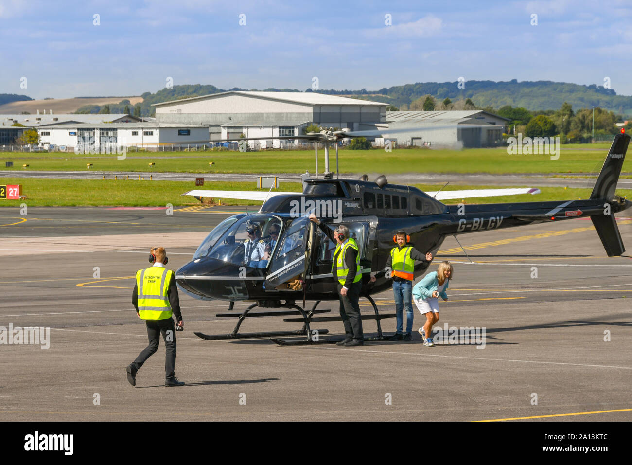 GLOUCESTER, ENGLAND - September 2019: Leute, die aus einem Bell Jetranger betrieben von Heli-Flight nach einem Rundflug von Gloucester Staverton Stockfoto