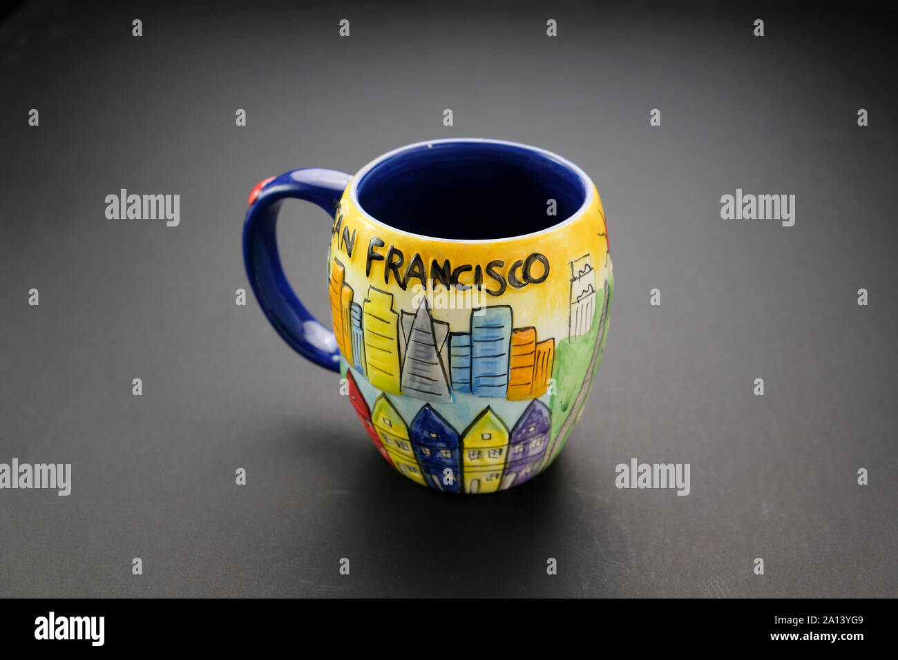 Farbenfrohe Kaffeetasse mit San Francisco-Schriftzug und blauer Blende auf dunklem Hintergrund Stockfoto