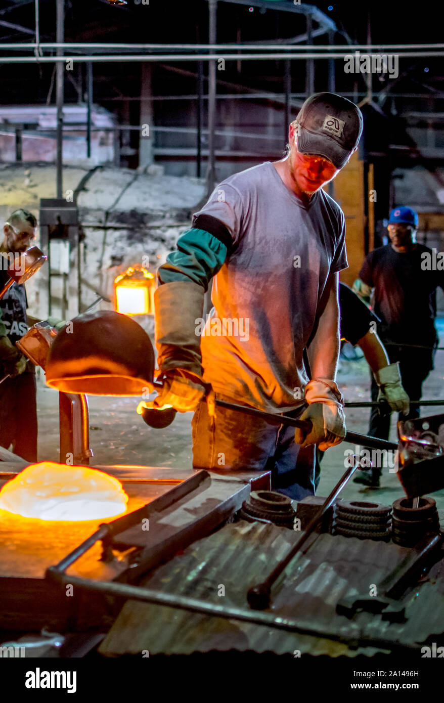 Sept 27 2019 Kokomo Indiana USA; ein Arbeiter dumps einen Stapel von geschmolzenem Glas aus einem tiegel Schöpfkelle, auf einem Metalltisch, wo es zu Verwirbelungen gearbeitet wird Stockfoto