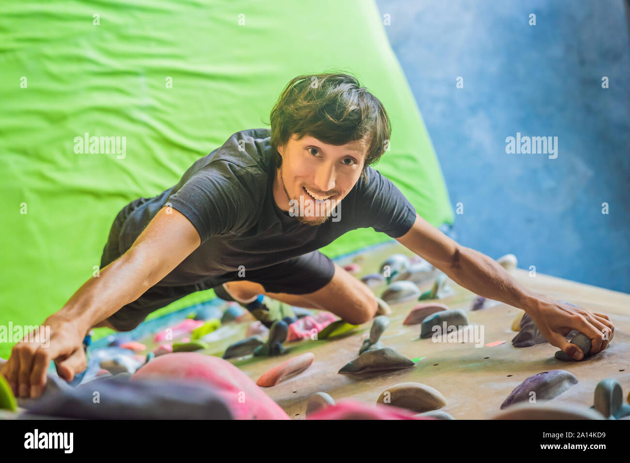 Muskulöse Mann üben Klettern auf einem Felsen an der Wand im Innenbereich Stockfoto