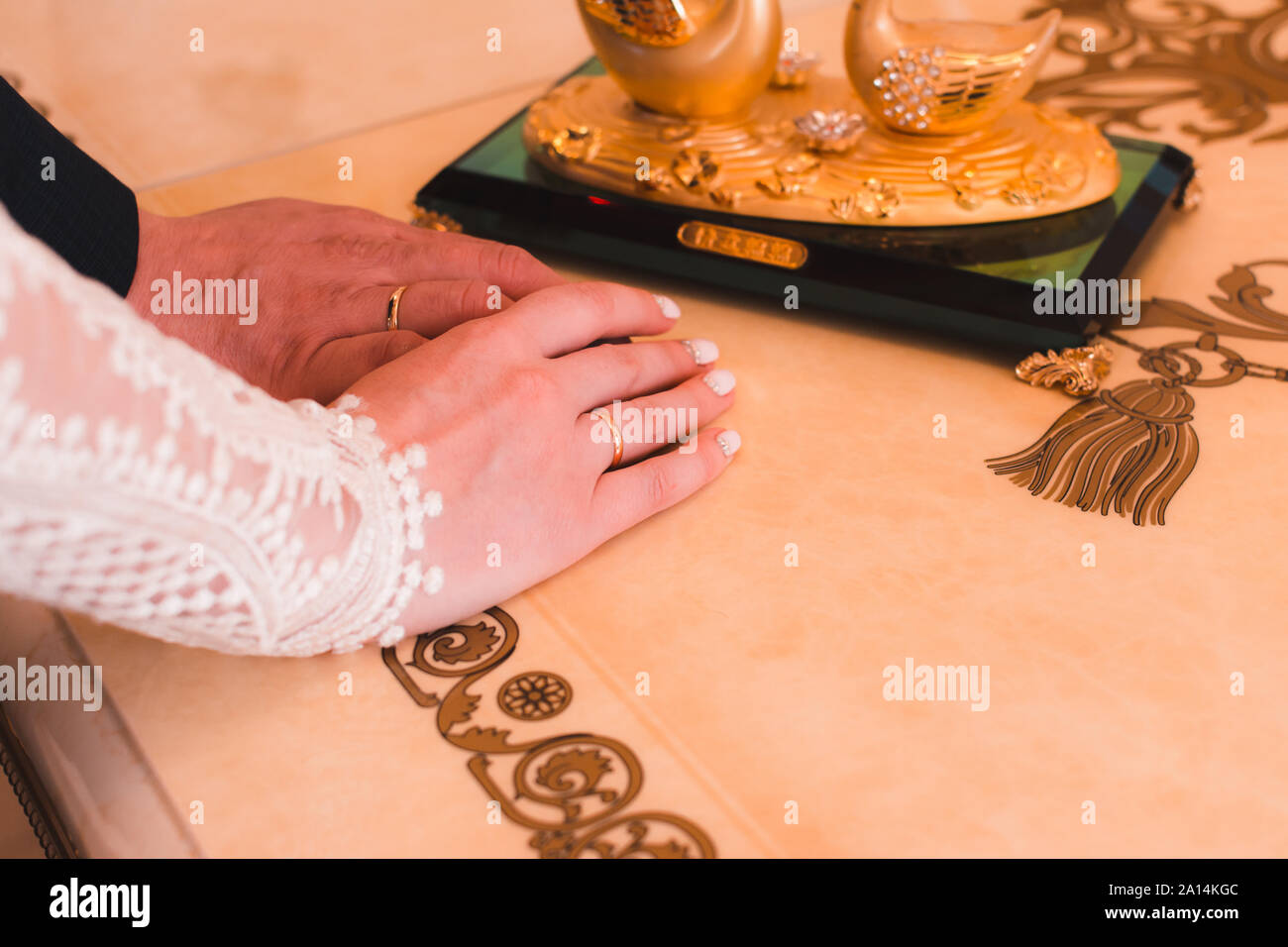 Die Hände des Brautpaares mit Hochzeit Ringe nach der Trauung auf einem luxuriösen Tabelle, close-up Stockfoto