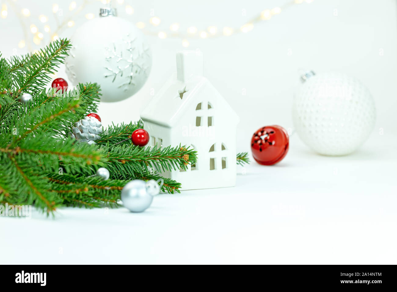 Winterurlaub Dekoration Konzept. Fir Tree Branch, dekorativen Kugeln aus Glas und Haus Spielzeug auf weißem Hintergrund Stockfoto