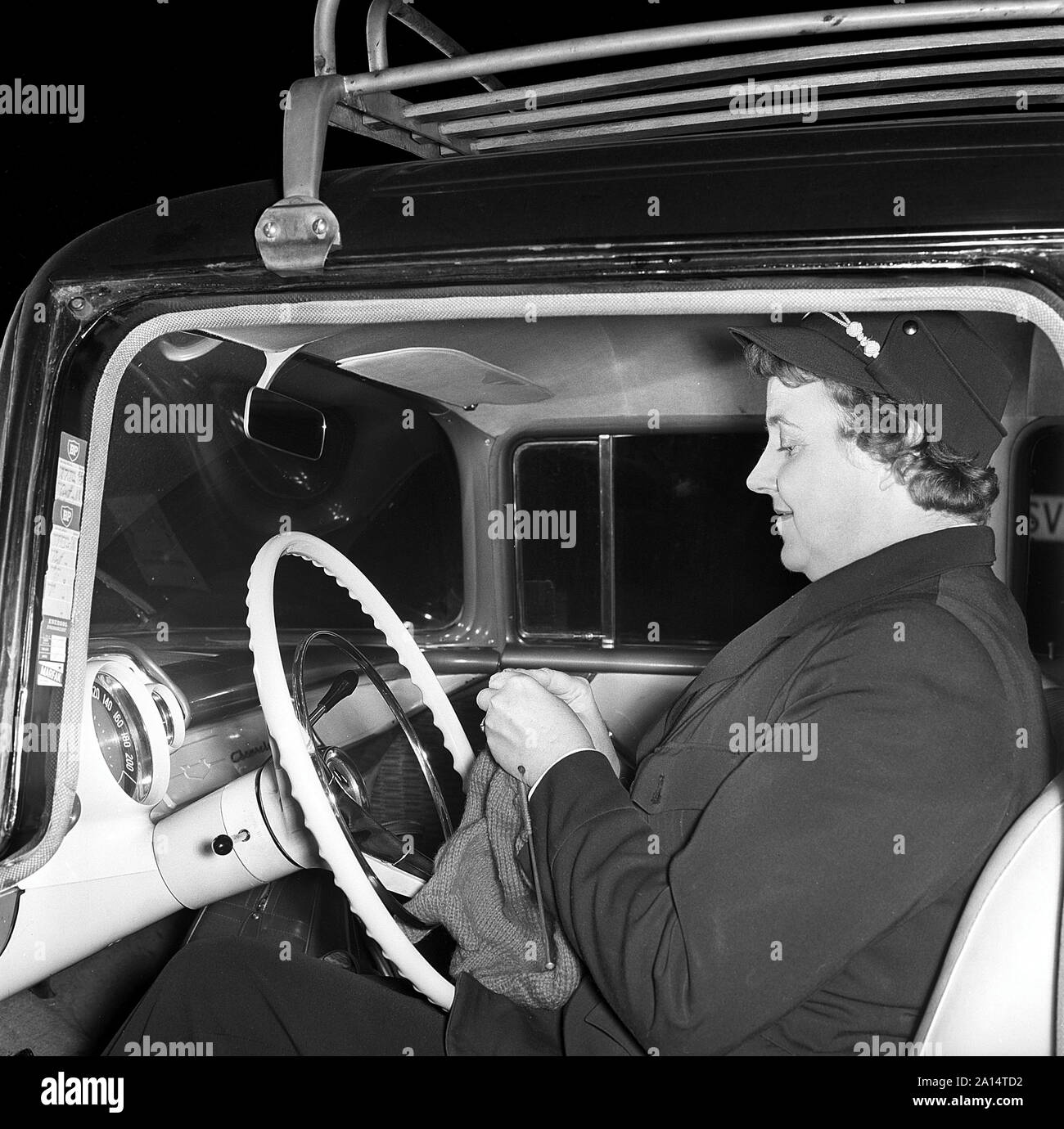 Taxifahrer in den 1950er Jahren. Eine weibliche Taxifahrer, die sich hinter dem Lenkrad in Ihr Taxi. Sie ist Stricken während des Wartens auf einen Client. Schweden 1958 Kristoffersson ref CC 59-5 Stockfoto