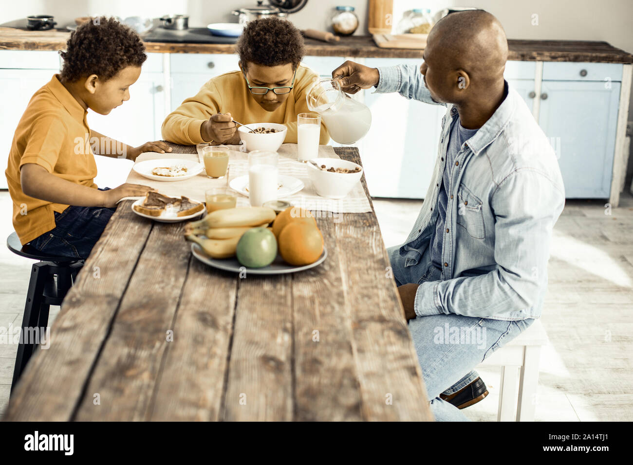 Familie von Papa und zwei Jungs beim Frühstück in der Küche. Stockfoto