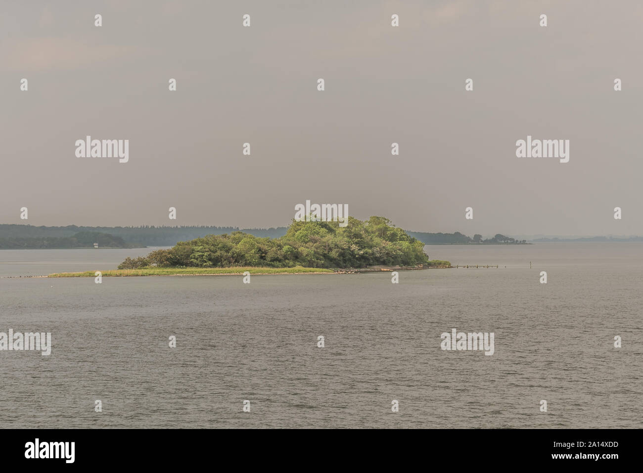 Eine kleine Insel mit grünen Bäumen und einem Steg im Meer in der Nähe von Svendborg, Dänemark, 13. Juli 2019 Stockfoto