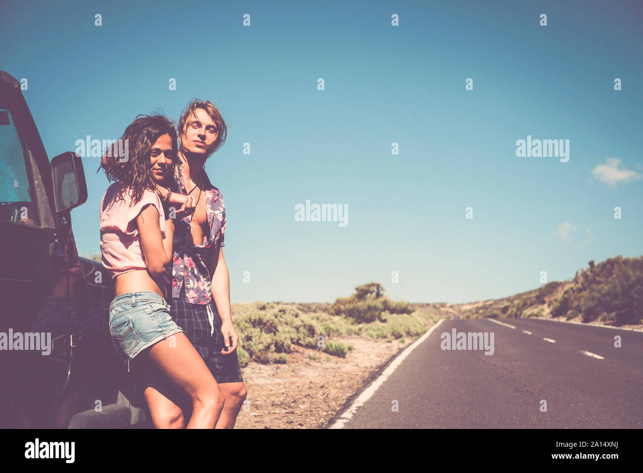 Vintage Style kaukasischen junge schöne Paar stehen und umarmen außerhalb ein schwarzes Auto während alternative Reisen Urlaub. Zusammen - Begriff der yout Stockfoto