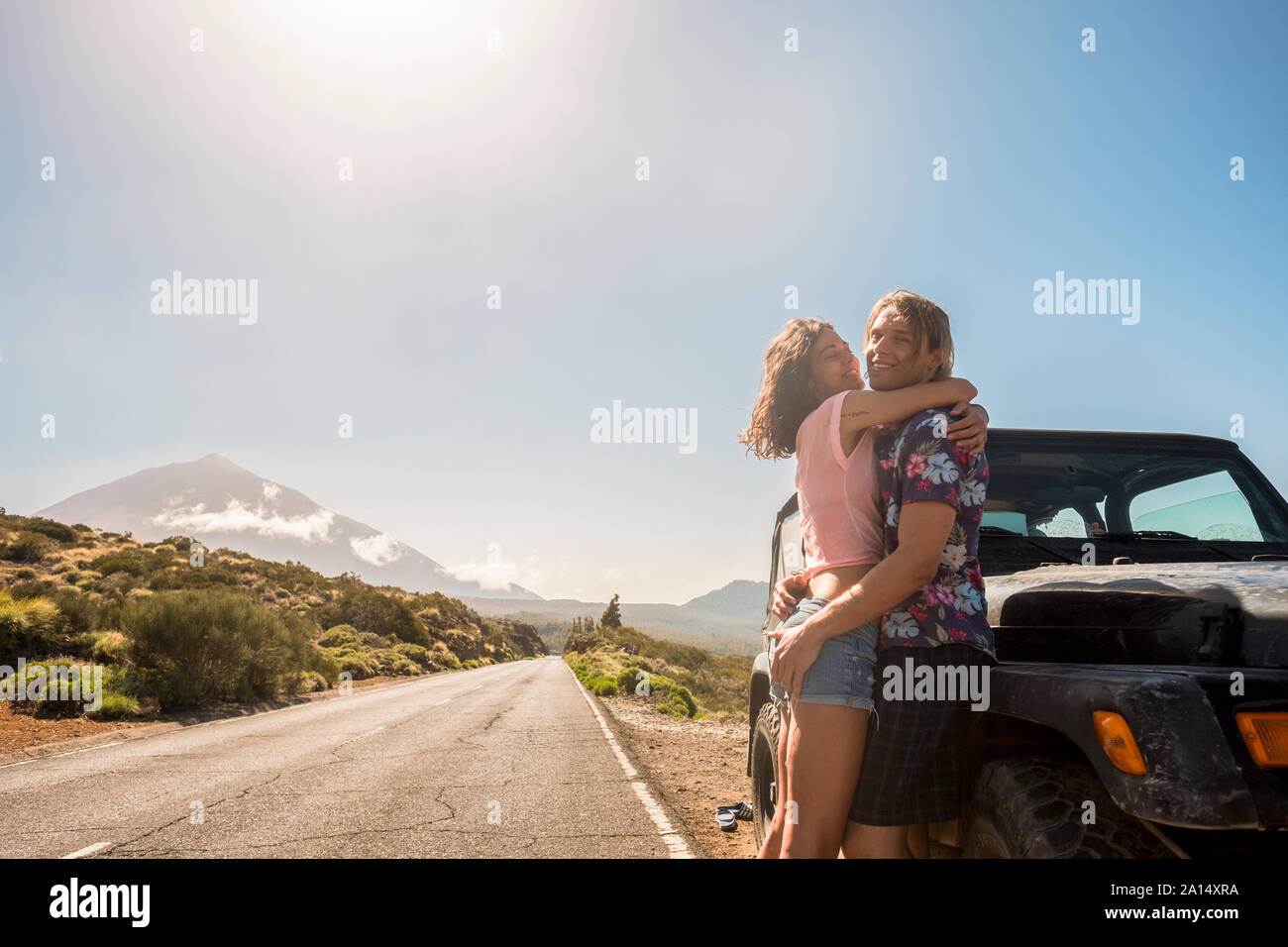 Sonnigen Stil kaukasischen junge schöne Paar stehen und umarmen außerhalb ein schwarzes Auto während alternative Reisen Urlaub. Zusammen - Begriff des youthf Stockfoto Sonnigen Stil kaukasischen junge schöne Paar stehen und umarmen außerhalb ein schwarzes Auto während alternative Reisen Urlaub. Zusammen - Begriff des youthf Stockfoto