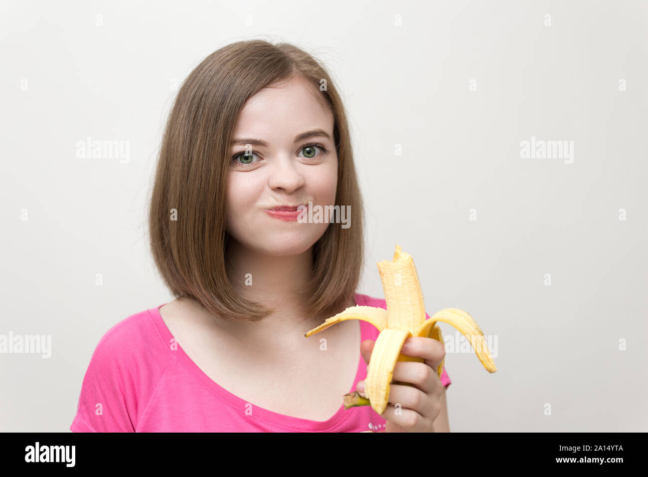 Portrait von lächelnden kaukasische Frau Mädchen Essen und Kauen gelbe Banane in der Hand. Gesunder Lebensstil, Obst vegetarische Ernährung. Stockfoto