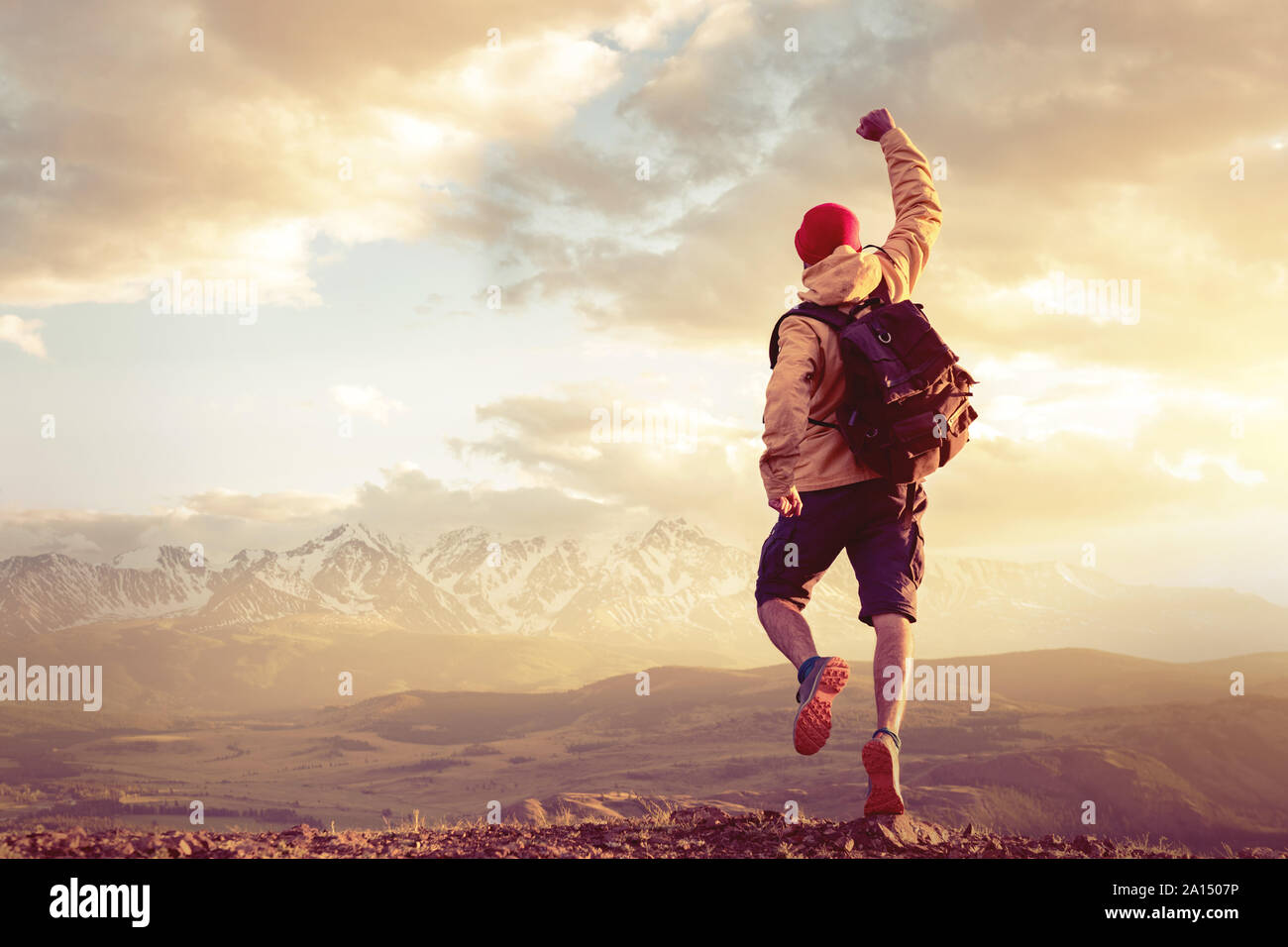 Happy Wanderer Mann springt in Sieger stellen gegen epische Sonnenuntergang Berge und Himmel Stockfoto