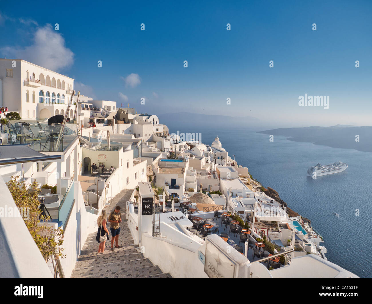 Malerische Aussicht auf den berühmten weißen Stadt Fira am Meeresufer mit Touristen und Segelschiff in Santorini Griechenland an einem sonnigen Tag Stockfoto