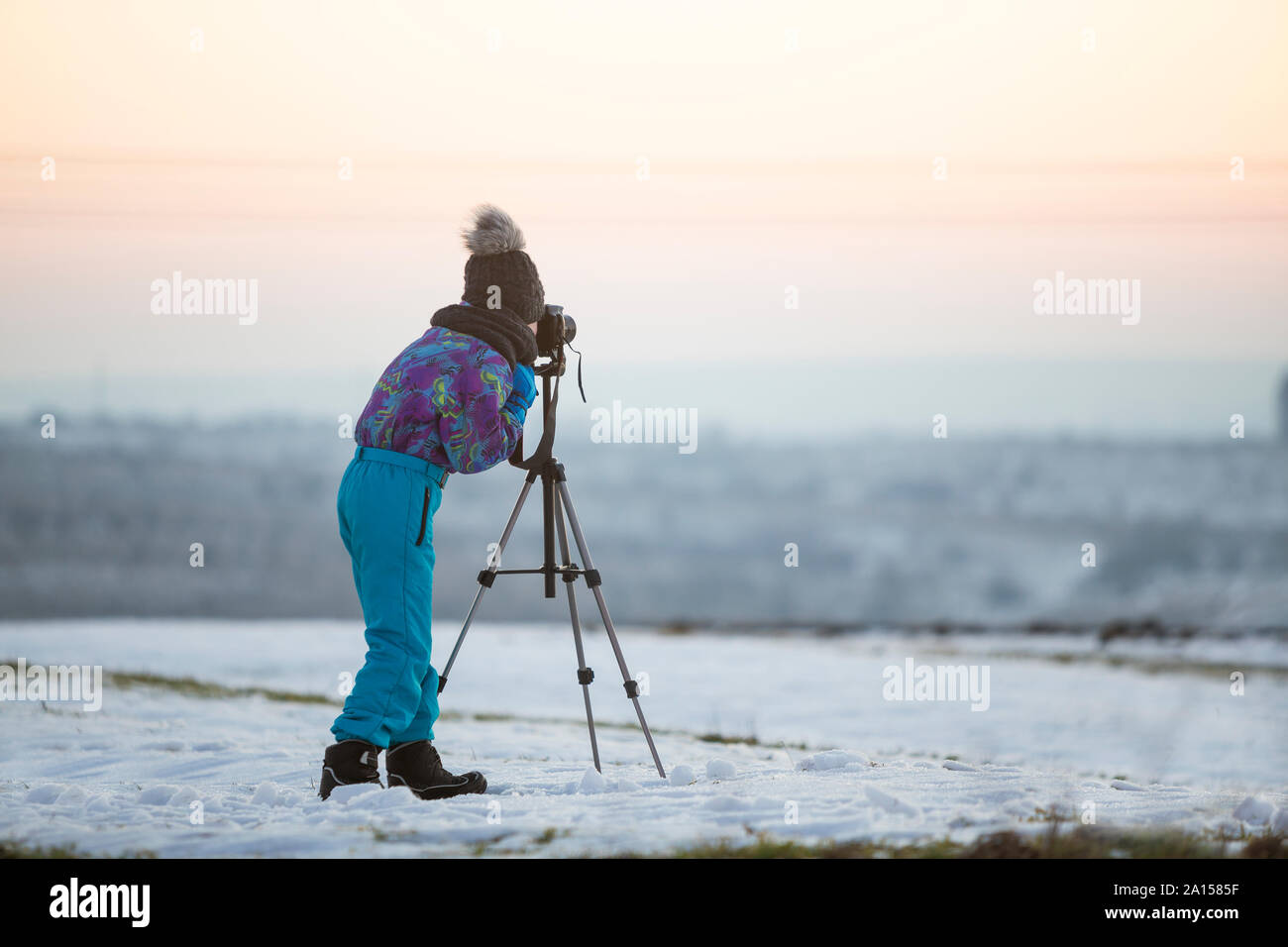 Kind Junge Fotografieren im Winter draußen mit Foto Kamera auf einem Stativ auf schneebedeckten Feld. Stockfoto