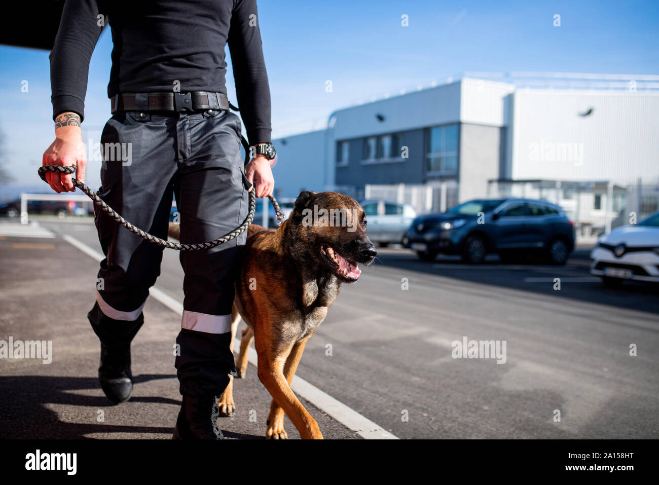Hundeführer auf Patrouille an einem Industriestandort mit seinem Hund an der Leine gehalten Stockfoto