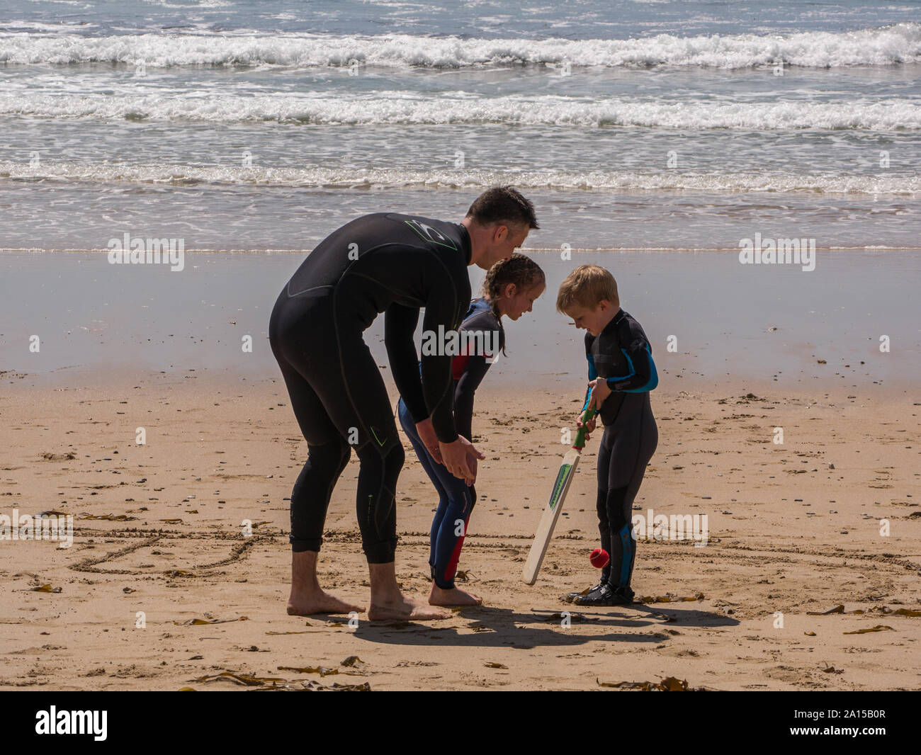 Ein Vater und zwei Söhne Kricket spielen am Strand Stockfoto