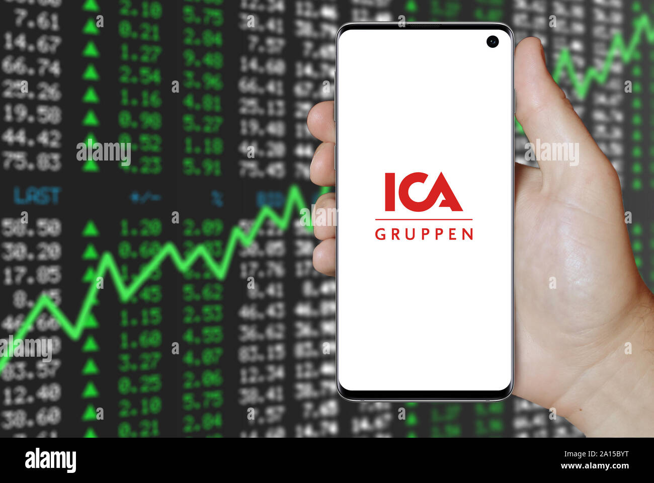 Ein Mann hält ein Smartphone mit dem Logo der Firma ICA-Gruppen im OMX Stockholm aufgeführt. Positive Börse Hintergrund. Credit: PIXDUCE Stockfoto