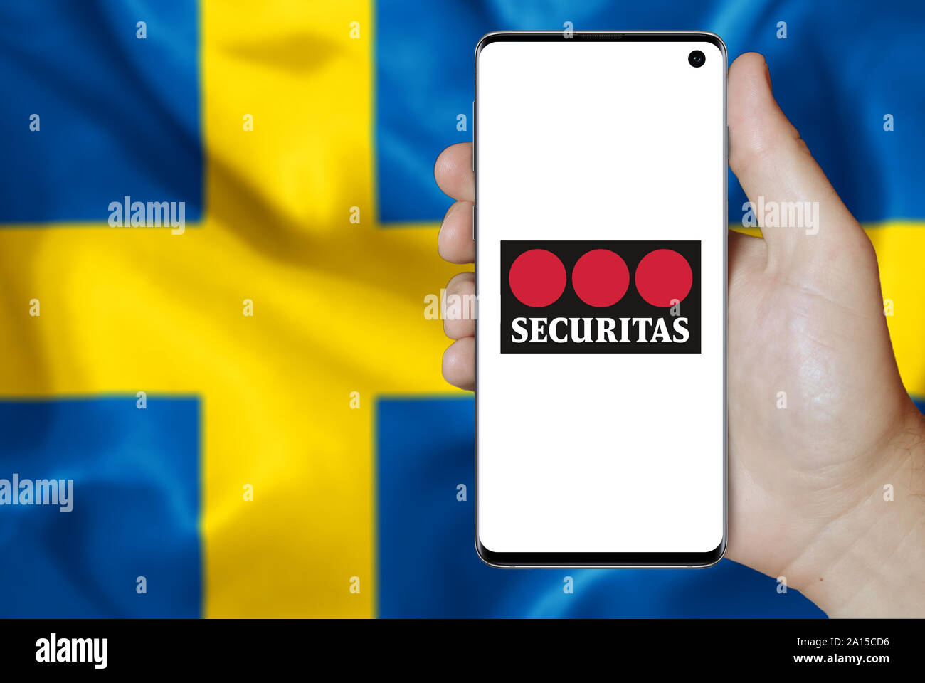 Ein Mann hält ein Smartphone mit dem Logo der Firma Securitas im OMX Stockholm aufgeführt. Schwedische Flagge im Hintergrund. Credit: PIXDUCE Stockfoto