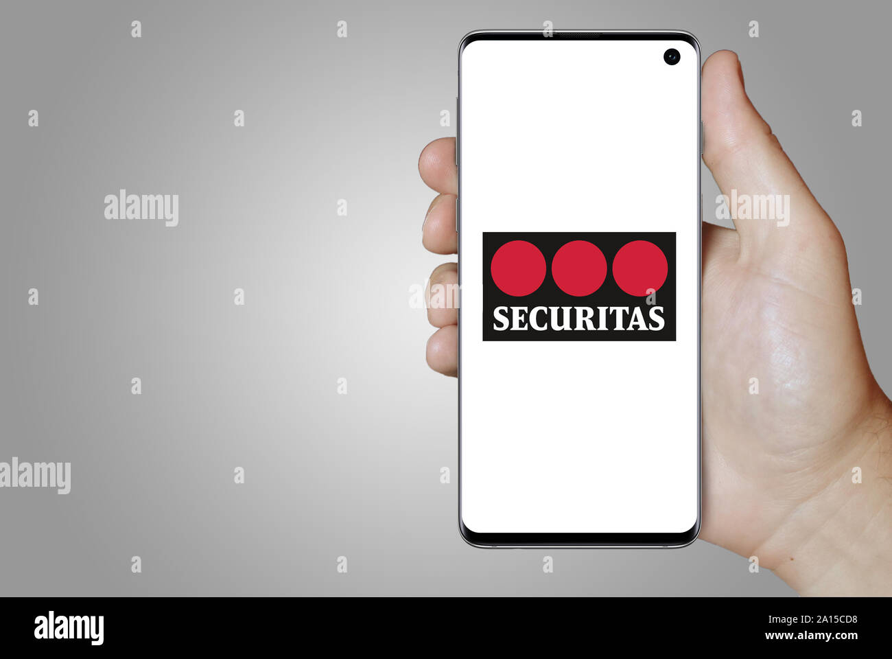 Ein Mann hält ein Smartphone mit dem Logo der Firma Securitas im OMX Stockholm aufgeführt. Grauen Farbverlauf im Hintergrund. Credit: PIXDUCE Stockfoto
