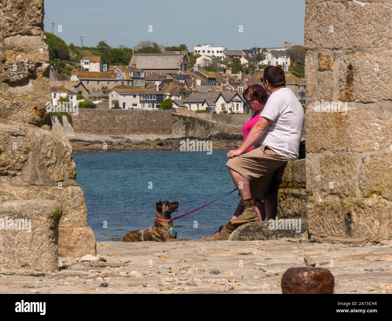 Zwei Personen und ein Hund sitzt auf einem Felsen auf St. Michael's Mount Stockfoto