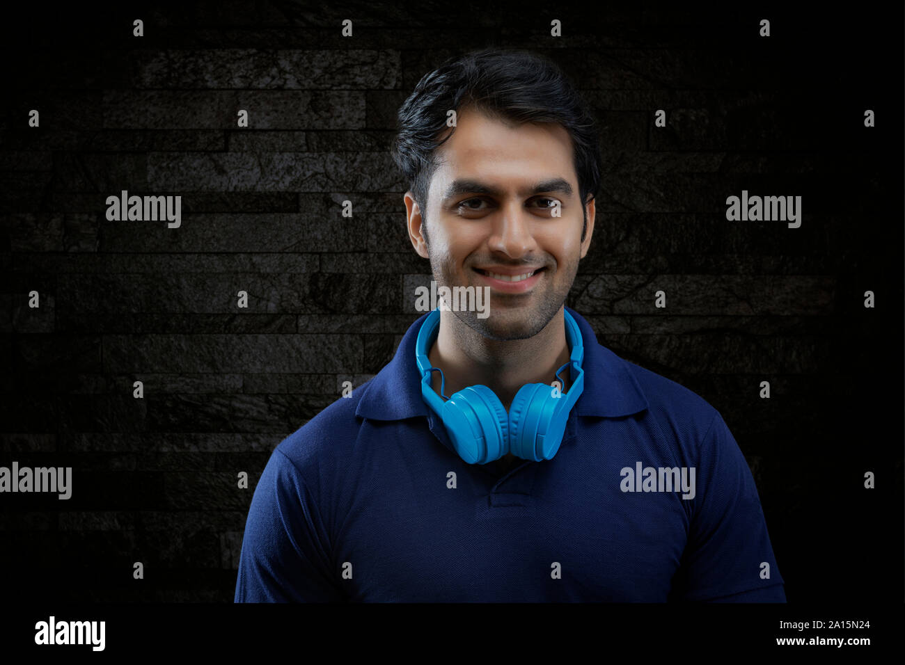 Portrait von lächelnden Mann mit Kopfhörer am Hals über schwarzen Hintergrund Stockfoto