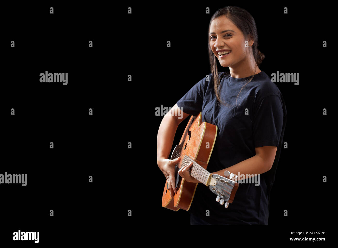 Junge Frau mit Gitarre auf schwarzem Hintergrund Stockfoto