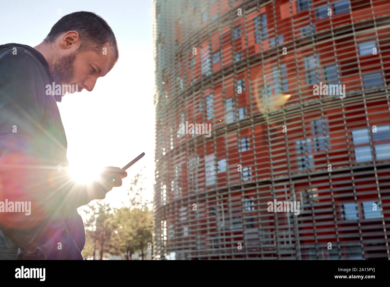 Mann mit Handy bei Sonnenuntergang in der Stadt, Barcelona, Spanien Stockfoto