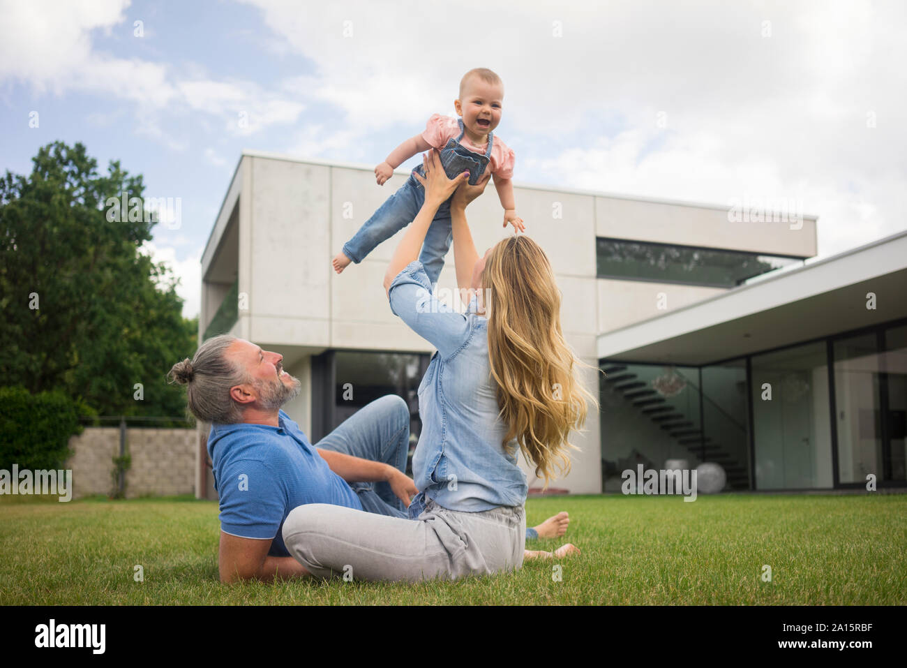 Glückliche Mutter mit Vater anheben Baby Mädchen im Garten Stockfoto