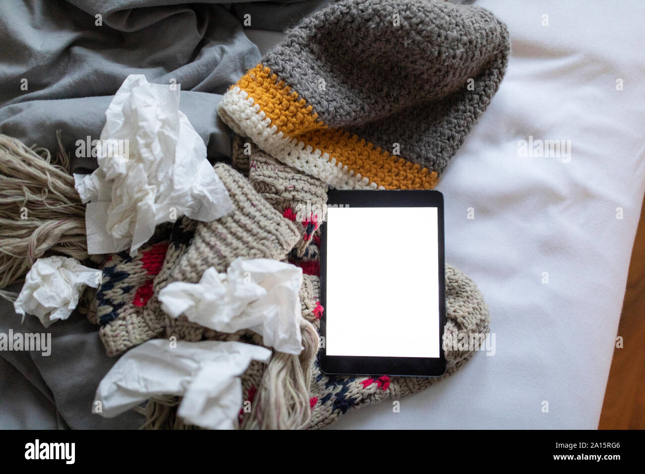 Gewebe, Tablet und warme Kleidung auf dem Bett liegend Stockfoto