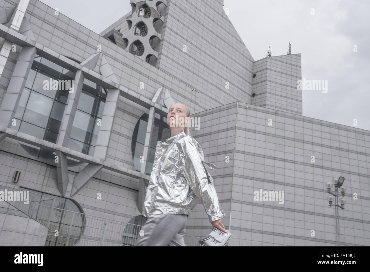 Cool girl in Silber passt die VR Brille in einer futuristischen Stadt Stockfoto