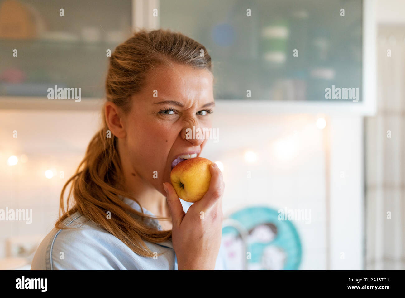 Porträt der jungen Frau einen Apfel essen zu Hause Stockfoto