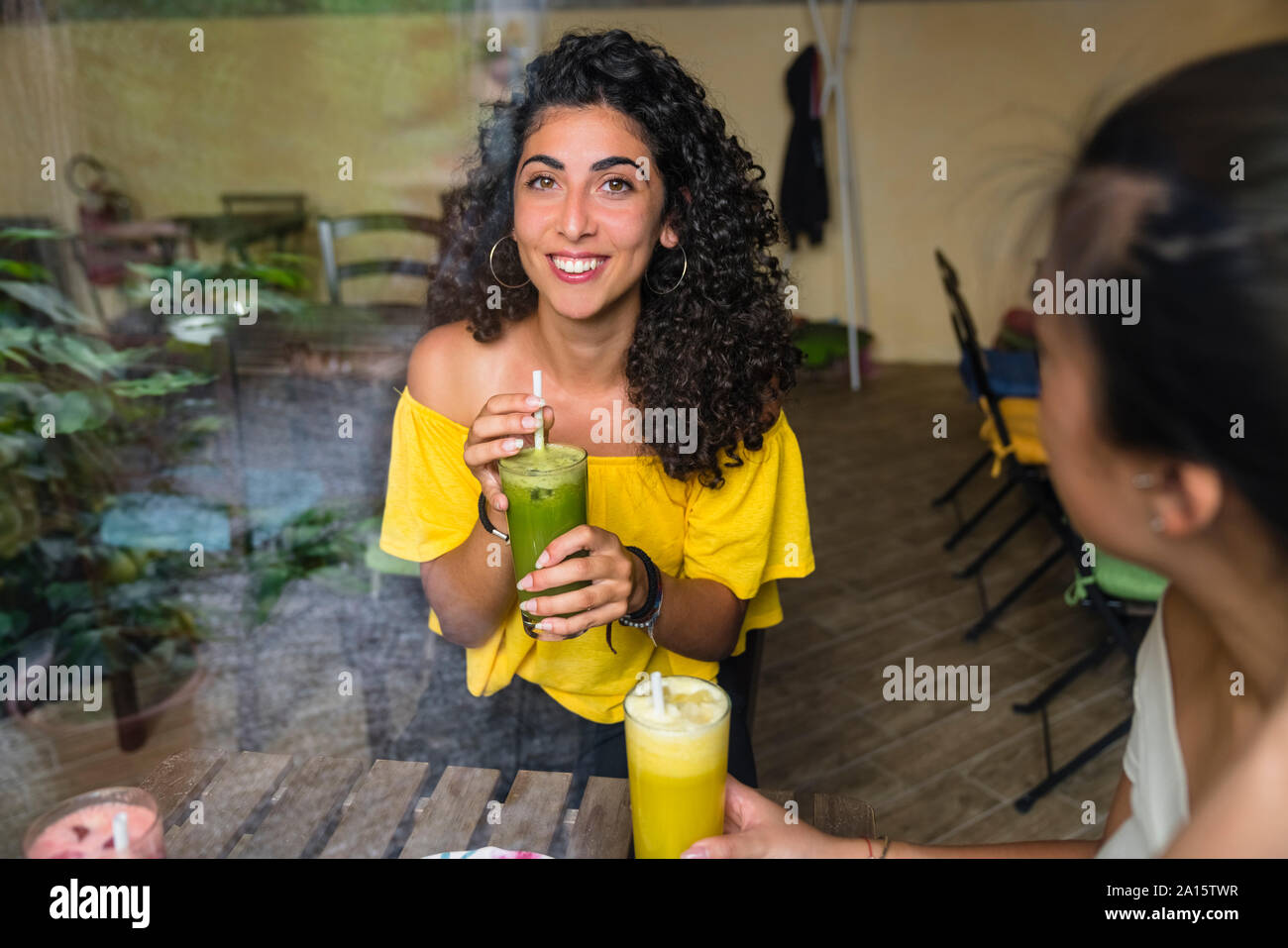 Portrait von lächelnden jungen Frau mit einem gesunden Drink in einem Bistro Stockfoto