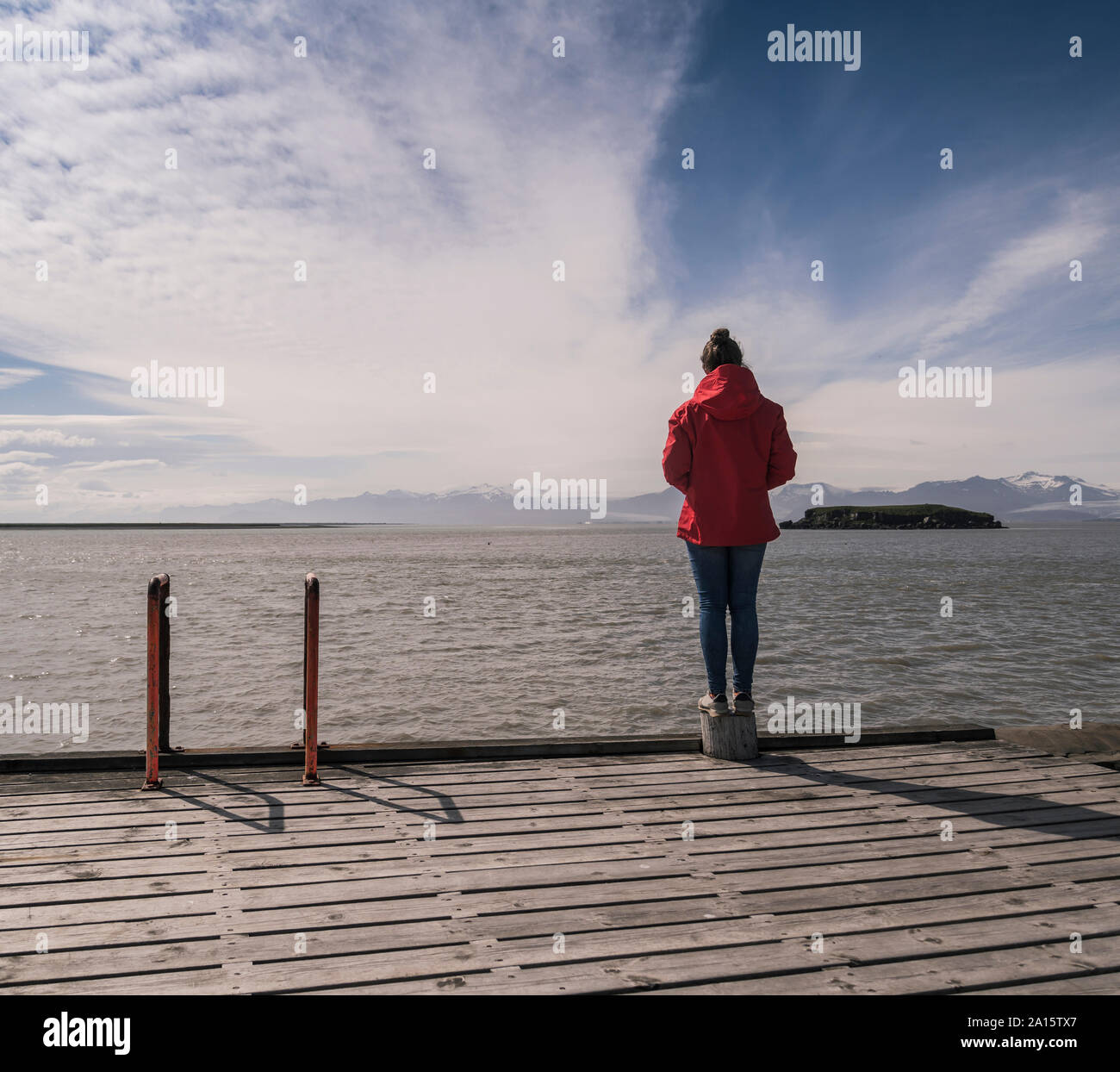 Junge Frau standig auf einem Steg, mit Blick auf das Meer, South East Iceland Stockfoto