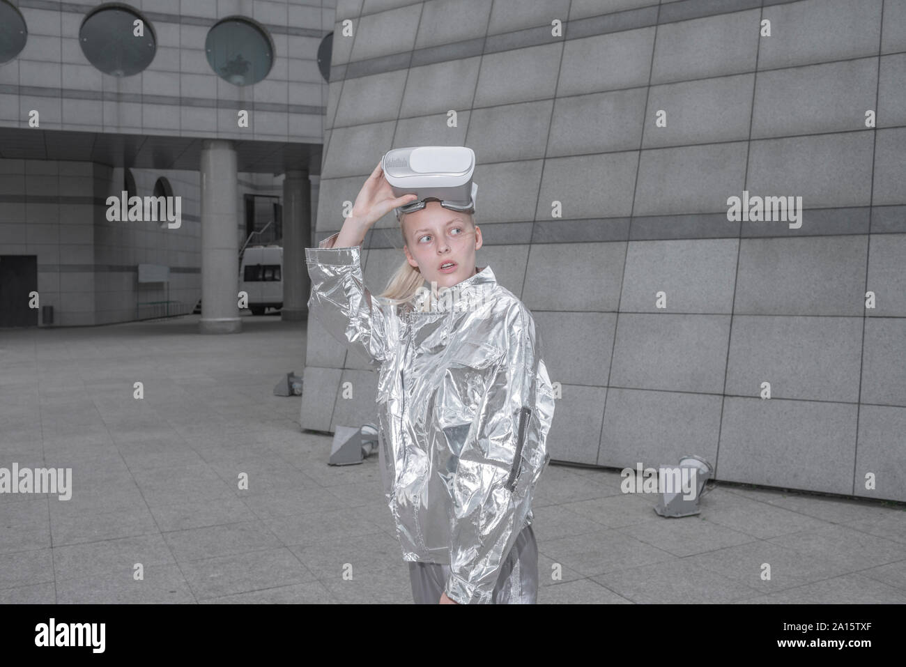 Cool girl in Silber Anzug tragen VR-Brille in einer futuristischen Stadt Stockfoto