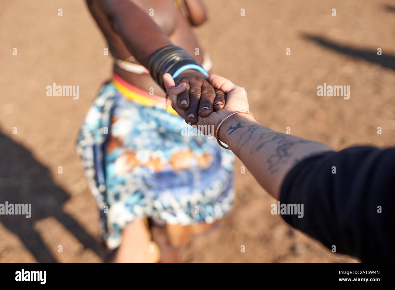 Muhacaona traditionelle Frau und weiße Frau, Hände halten, Oncocua, Angola Stockfoto