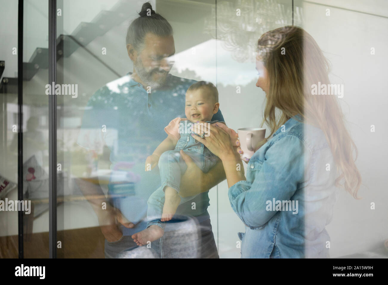Glückliche Familie von drei Ständigen hinter dem Fenster zu Hause Stockfoto