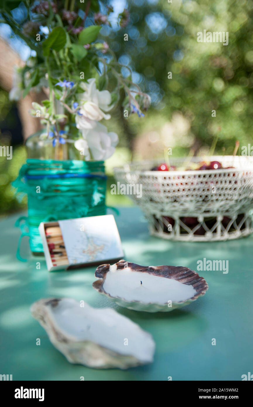 Anti Moskito Kerzen in Jakobsmuscheln mit Matchbox und Obstkorb im Hintergrund Stockfoto